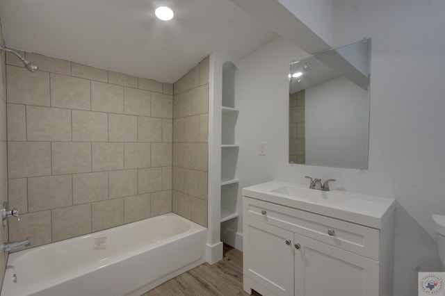 full bathroom featuring wood-type flooring, tiled shower / bath combo, vanity, and toilet