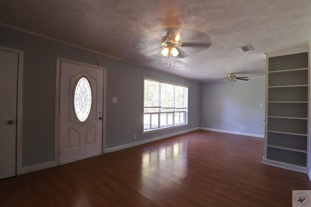 foyer entrance with dark wood-type flooring, a textured ceiling, ceiling fan, and ornamental molding