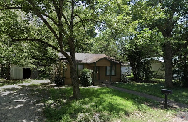 view of front of property with a front yard and a storage shed