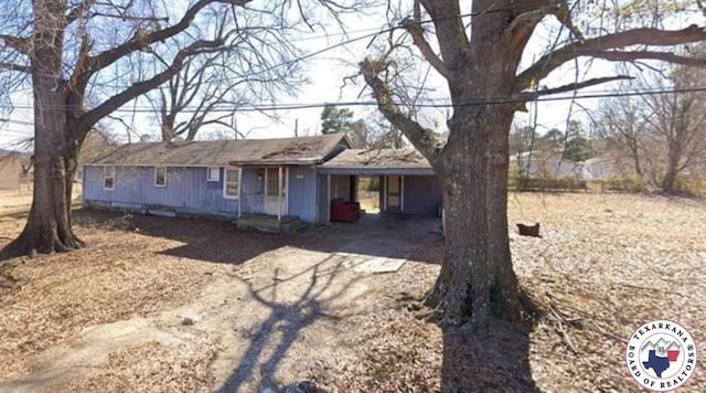 1018 Plum St, Texarkana, TX 75501 - ranch-style house with dirt driveway, an attached carport, and board and batten siding
