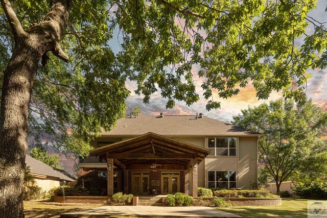 back of house at dusk featuring a ceiling fan and french doors