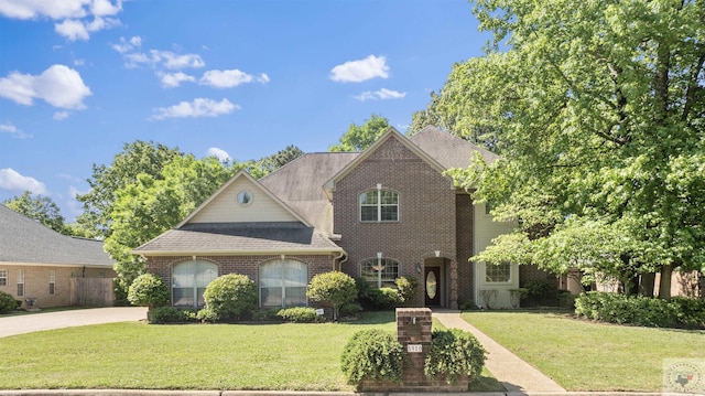 view of front of home featuring a shingled roof, brick siding, and a front lawn