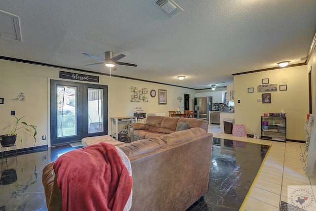 living room with ceiling fan, french doors, light tile patterned floors, a textured ceiling, and ornamental molding