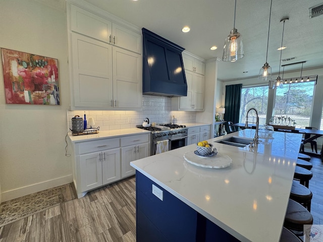 kitchen featuring tasteful backsplash, double oven range, a breakfast bar area, light countertops, and a sink