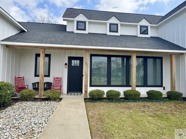 view of front of property featuring board and batten siding, a porch, a front lawn, and a shingled roof