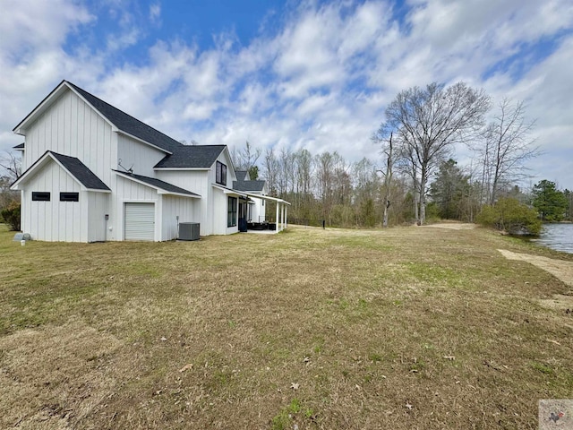 view of side of property featuring a yard, central AC unit, board and batten siding, and a shingled roof