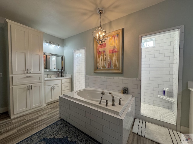 full bathroom with vanity, wood finished floors, tiled shower, an inviting chandelier, and a garden tub