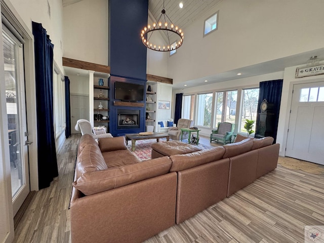 living room with a chandelier, lofted ceiling, recessed lighting, light wood-style flooring, and a fireplace