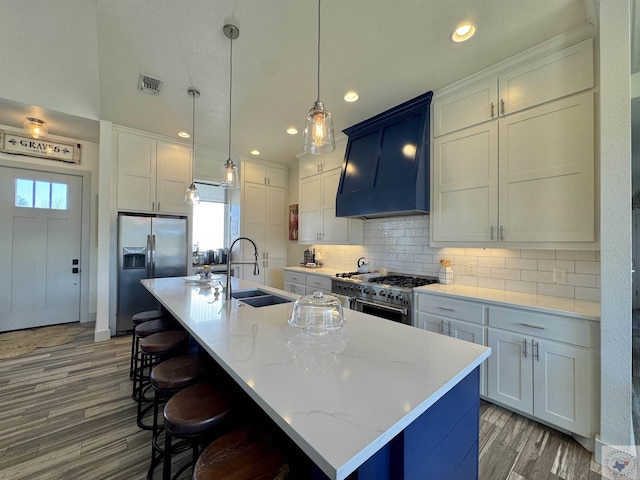 kitchen featuring visible vents, backsplash, premium range hood, appliances with stainless steel finishes, and a sink