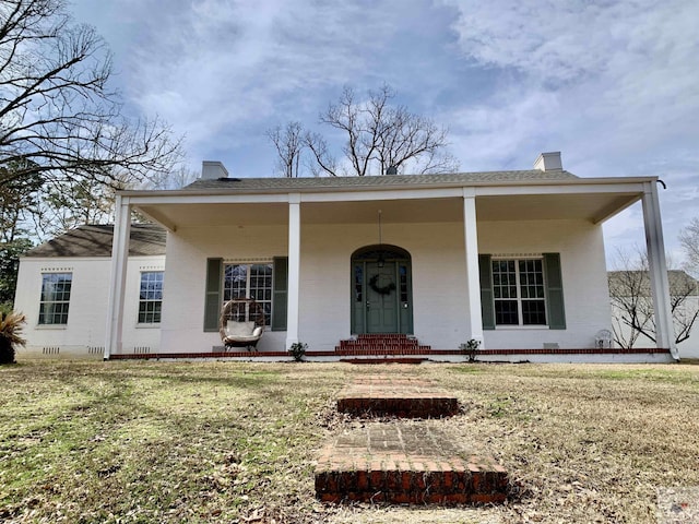 view of front of house featuring a porch, a shingled roof, crawl space, a chimney, and a front yard