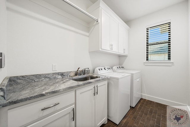 washroom with washer and clothes dryer, a sink, cabinet space, and baseboards