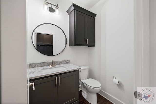 bathroom featuring baseboards, vanity, toilet, and wood finished floors