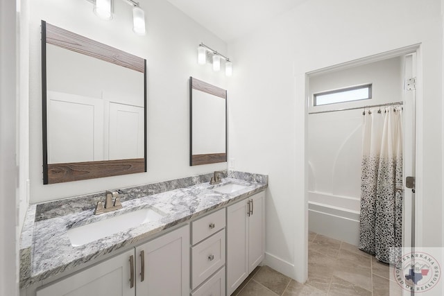 full bath with double vanity, shower / bathtub combination with curtain, baseboards, and a sink