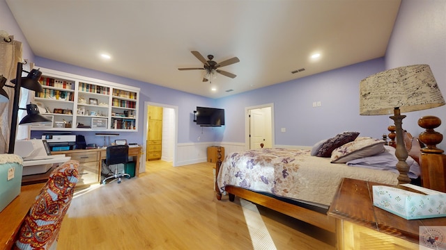 bedroom with ceiling fan, connected bathroom, built in desk, and wood-type flooring