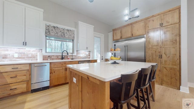 kitchen featuring appliances with stainless steel finishes, a kitchen island, white cabinetry, tasteful backsplash, and hanging light fixtures