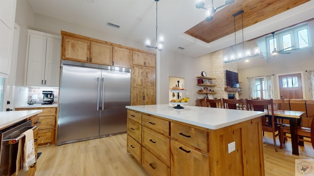 kitchen with pendant lighting, a kitchen island, light hardwood / wood-style floors, and appliances with stainless steel finishes