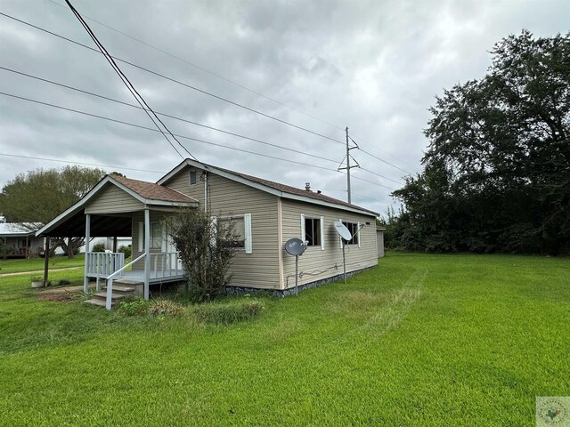 view of side of home featuring covered porch and a yard