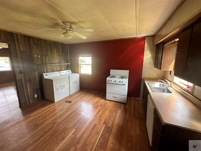 kitchen featuring a textured ceiling, sink, light wood-type flooring, washer and clothes dryer, and gas range gas stove