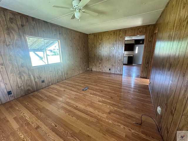 unfurnished room with ceiling fan and wooden walls