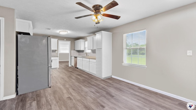 2401 E E Ave B, Hooks, TX 75561 - kitchen with appliances with stainless steel finishes, light wood finished floors, a ceiling fan, a sink, and tasteful backsplash