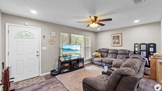 living area featuring plenty of natural light, wood finished floors, visible vents, and ceiling fan