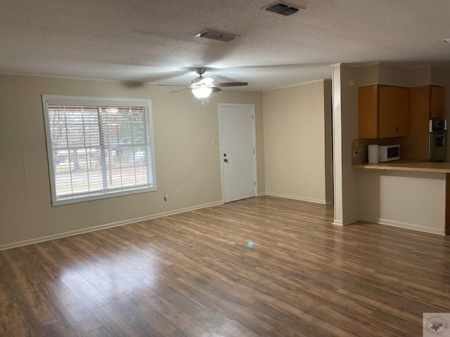 unfurnished living room with dark wood-style floors, ceiling fan, visible vents, and a textured ceiling