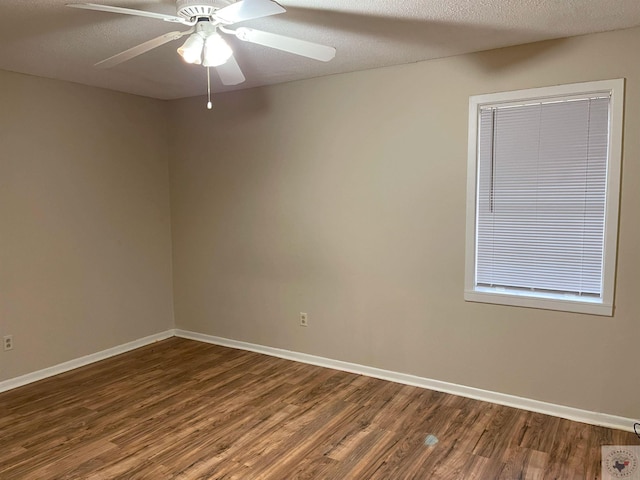 unfurnished room featuring a ceiling fan, baseboards, dark wood finished floors, and a textured ceiling