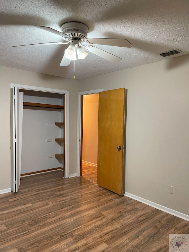 unfurnished bedroom with a closet, ceiling fan, a textured ceiling, wood finished floors, and baseboards