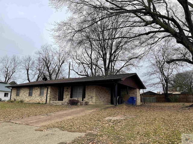 single story home featuring a carport, fence, concrete driveway, and brick siding