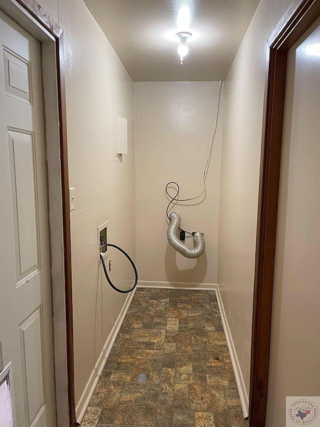 clothes washing area with hookup for a washing machine, stone finish flooring, laundry area, and baseboards