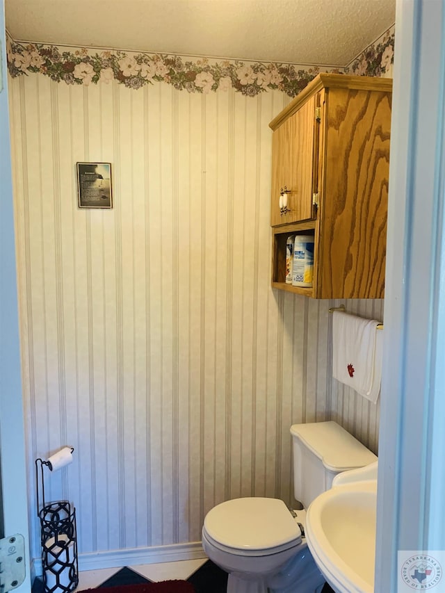 bathroom with sink, a textured ceiling, and toilet