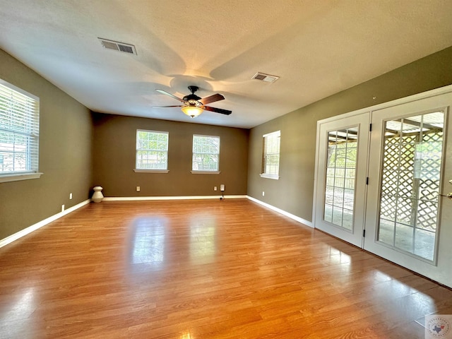 empty room featuring light hardwood / wood-style floors, plenty of natural light, a textured ceiling, and ceiling fan