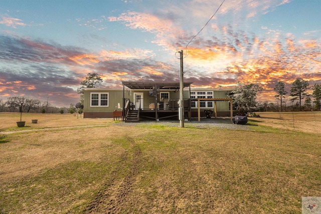 back of property at dusk featuring a deck and a lawn