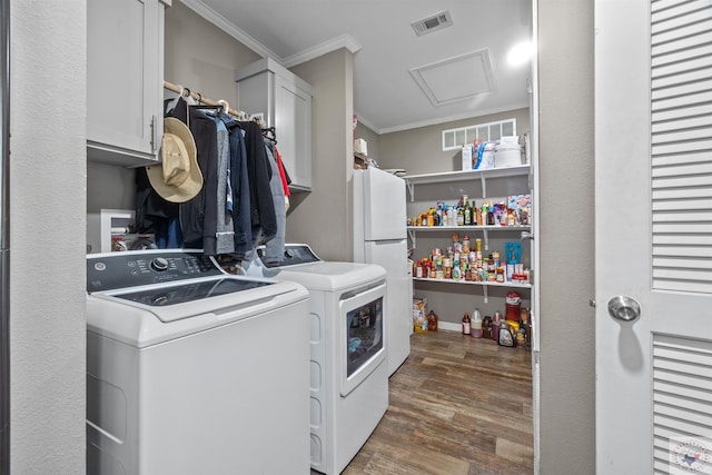 washroom featuring separate washer and dryer, wood finished floors, cabinet space, attic access, and crown molding