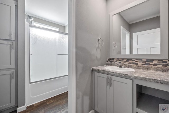 full bath with backsplash, ornamental molding, enclosed tub / shower combo, vanity, and wood finished floors