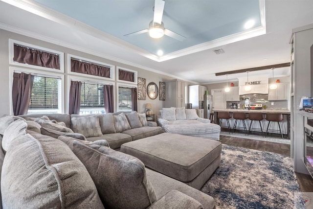 living area featuring crown molding, visible vents, a raised ceiling, and dark wood-style flooring