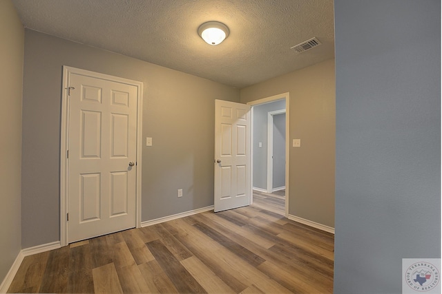 spare room with wood-type flooring and a textured ceiling