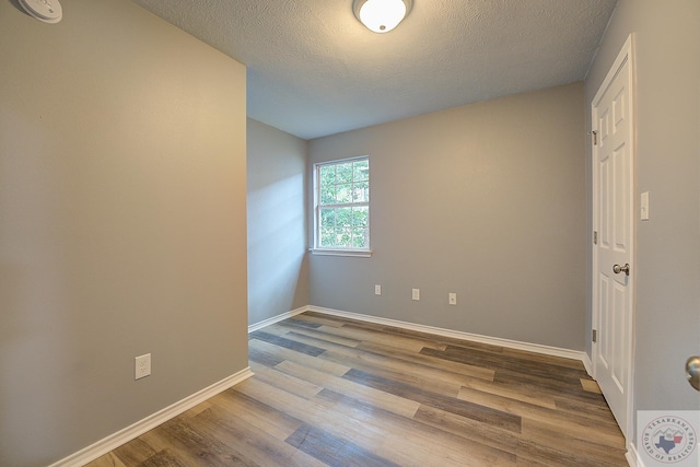 spare room featuring hardwood / wood-style flooring and a textured ceiling