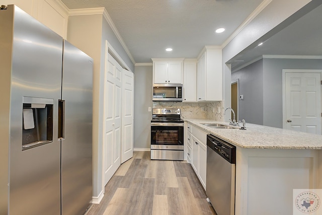 kitchen featuring sink, white cabinetry, light stone counters, decorative backsplash, and stainless steel appliances