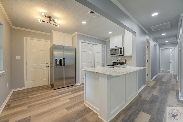 kitchen with light stone counters, hardwood / wood-style flooring, white cabinetry, and appliances with stainless steel finishes