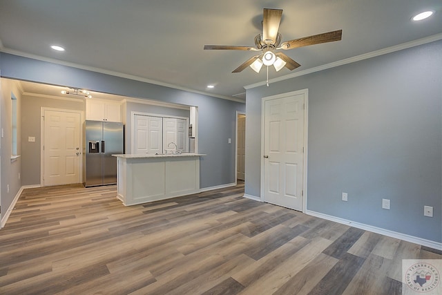 unfurnished living room with crown molding, light hardwood / wood-style floors, sink, and ceiling fan