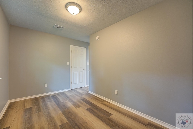 spare room featuring wood-type flooring and a textured ceiling