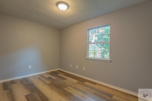 empty room with hardwood / wood-style floors and a textured ceiling