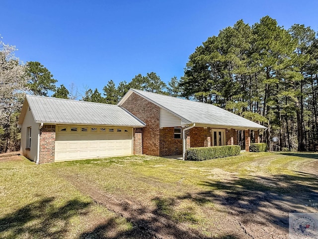 view of front facade featuring a front yard, a garage, brick siding, and driveway