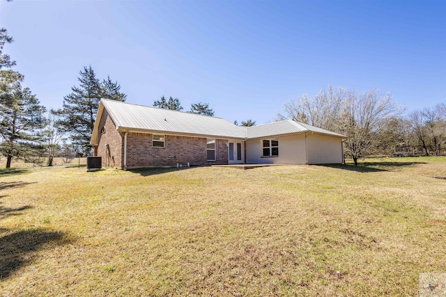 rear view of property with a lawn, brick siding, and metal roof