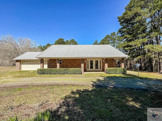 ranch-style home featuring a front yard, an attached garage, french doors, and brick siding