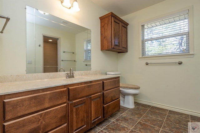 bathroom featuring baseboards, toilet, a healthy amount of sunlight, and vanity