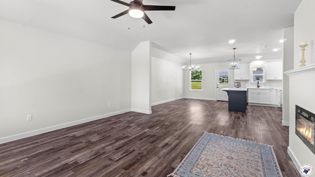 206 Spencer St, Maud, TX 75567 - unfurnished living room with a ceiling fan, a chandelier, dark wood-type flooring, recessed lighting, and a glass covered fireplace