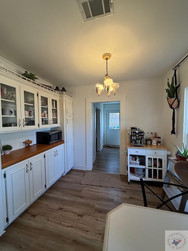 kitchen featuring dark wood-style floors, a notable chandelier, visible vents, stainless steel microwave, and wood counters