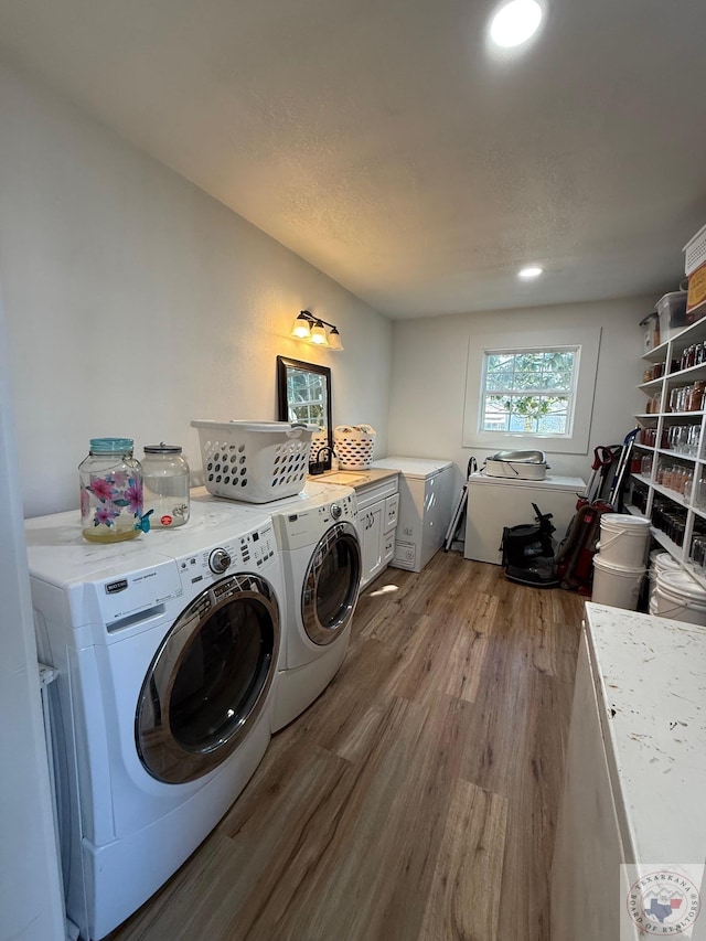 laundry area featuring independent washer and dryer, wood finished floors, and cabinet space